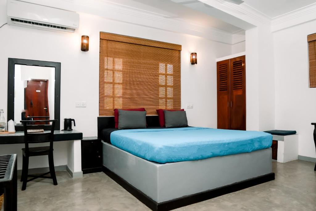 a bedroom with a bed and a desk and a chair at Seagreen Guesthouse - Galle Fort in Galle