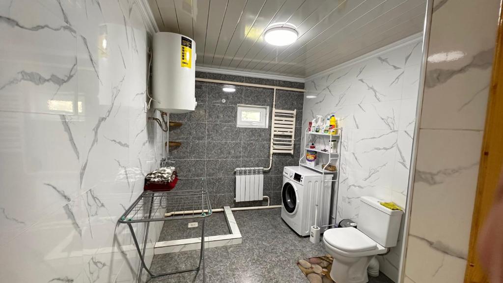 a bathroom with a toilet and a washing machine at NomadicaKyrgyz in Tërt-Kul'