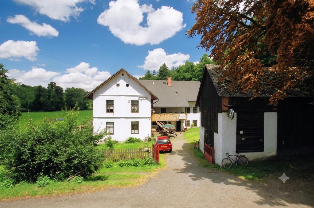 a white house with a garage next to a driveway at Petrovický mlýn in Kasanice