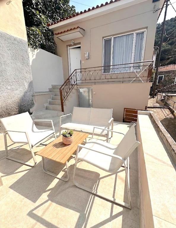 a patio with white chairs and a table and a house at Kayani View in Taxiárkhai