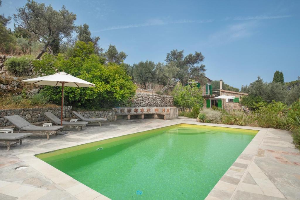 a swimming pool with an umbrella and chairs and a table at Can Carabá in Illes Balears