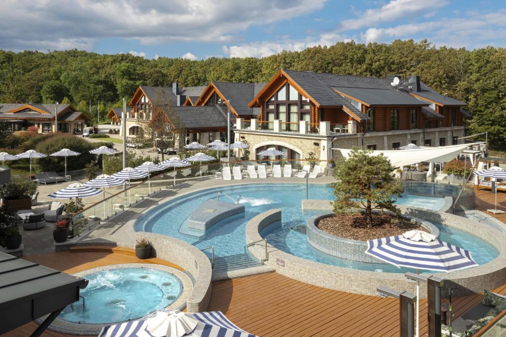 an outdoor swimming pool with chairs and umbrellas at Avalon Resort & SPA in Miskolctapolca