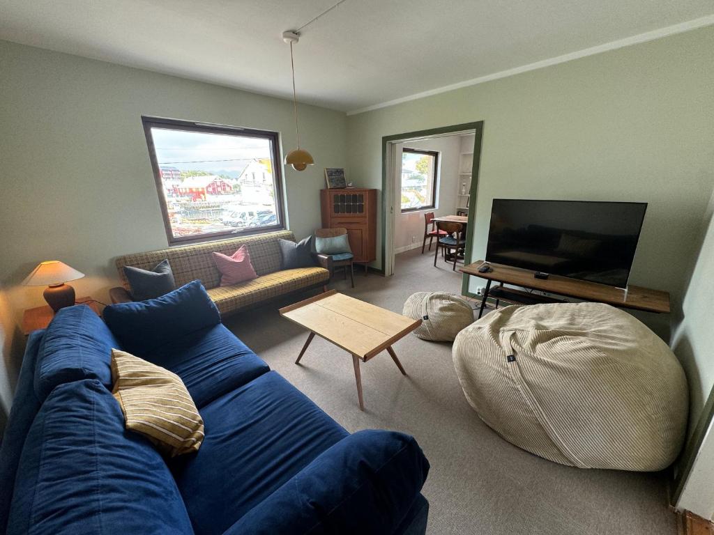 a living room with a blue couch and a flat screen tv at Malnestomten in Henningsvær