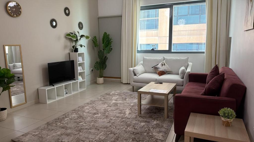 a living room with a couch and a tv at SPACIOUS 3 Bedroom Apartm Beach Front (Side View) in Abu Dhabi