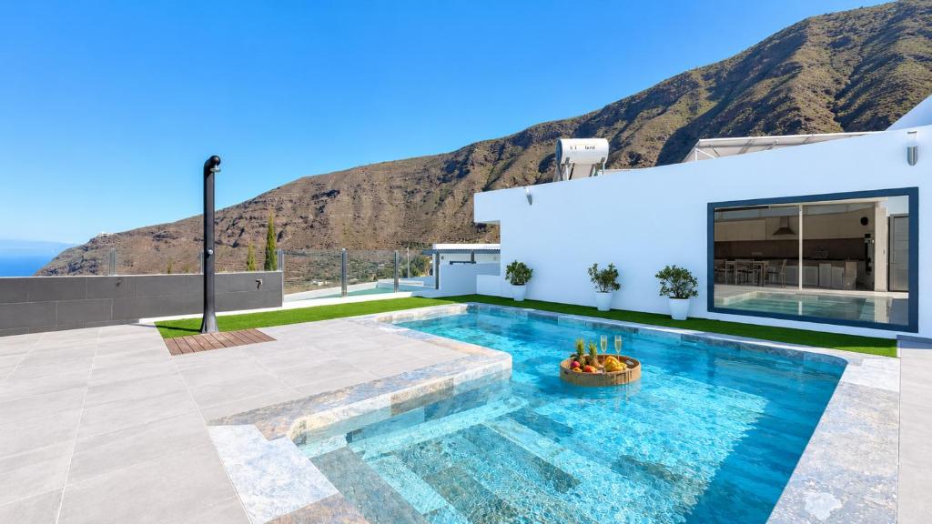a house with a swimming pool with a mountain in the background at JVG VILLAS - Villa Joval in Güimar