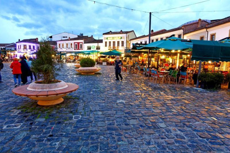 a group of people walking around a street with restaurants at ZA Apartment in Korçë
