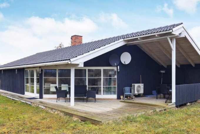 a blue house with a large deck with chairs at Coastal Hideout Vacation Home in Bøtø By