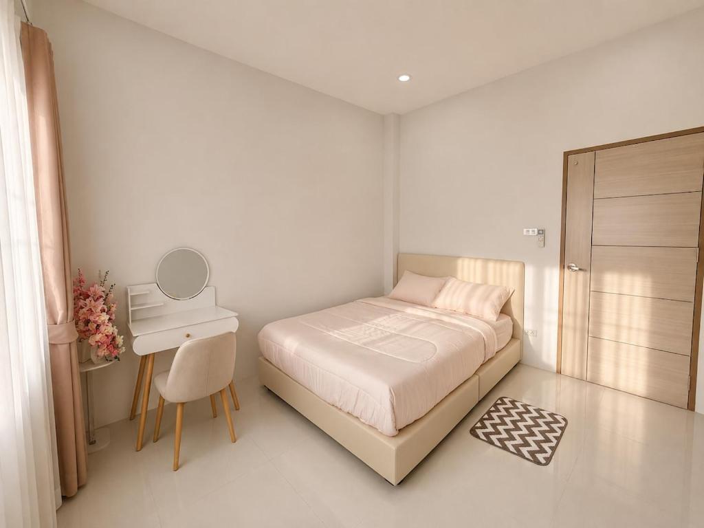 a white bedroom with a bed and a desk at Kulanat House in Chiang Mai