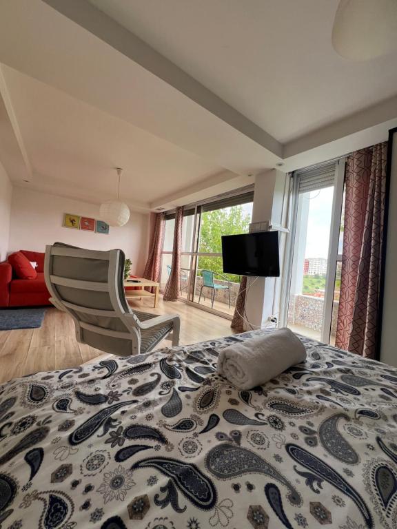 a bedroom with a bed and a chair and a television at Le Jardin Aparthotel in Taza