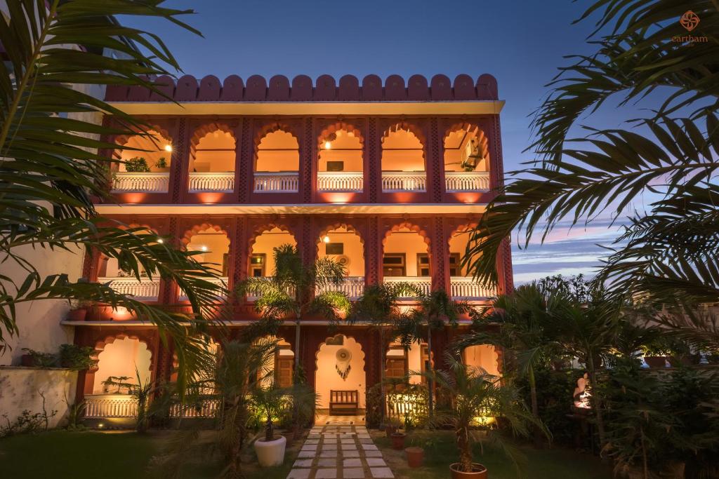 a large building with palm trees in front of it at Eartham Stays, Pushkar in Pushkar