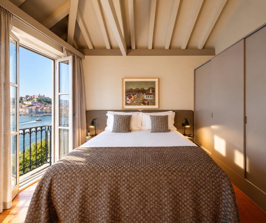 a bedroom with a large bed with a large window at Casa Zogbi Hotel in Porto