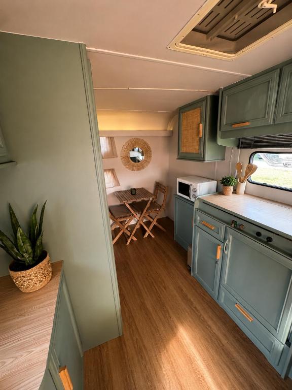 an rv kitchen with blue cabinets and a table at Caravana Lobo Camp in Boca de Huérgano