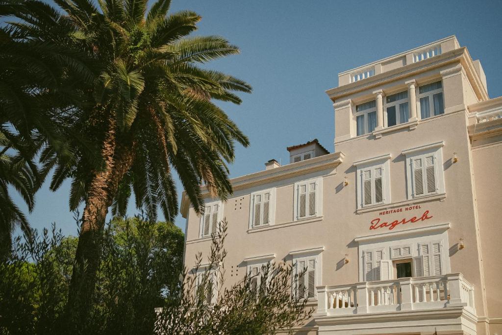 a building with a palm tree in front of it at Heritage Hotel Zagreb Dubrovnik in Dubrovnik