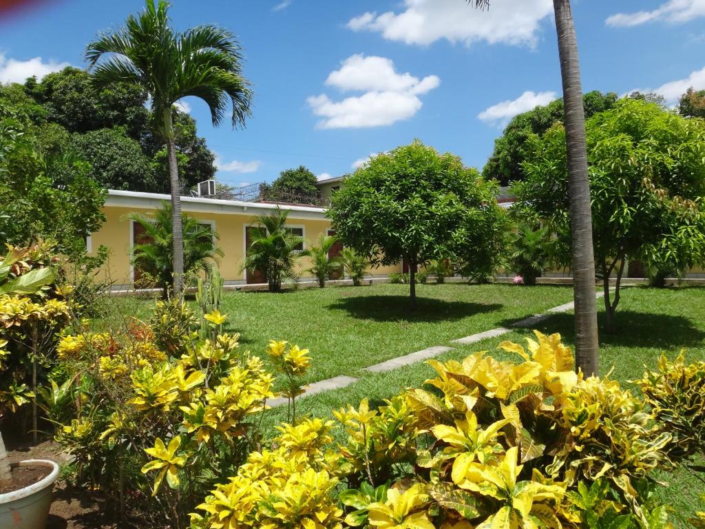 a garden with yellow flowers and palm trees at Hotel La Arboleda in Managua