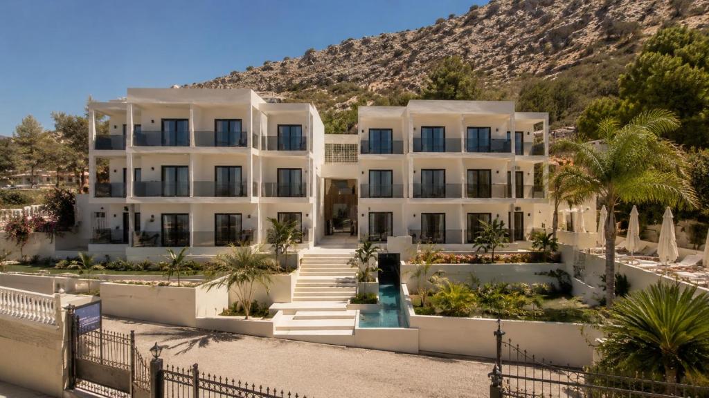 a large white building with palm trees in front of a mountain at Stella View in Pefki