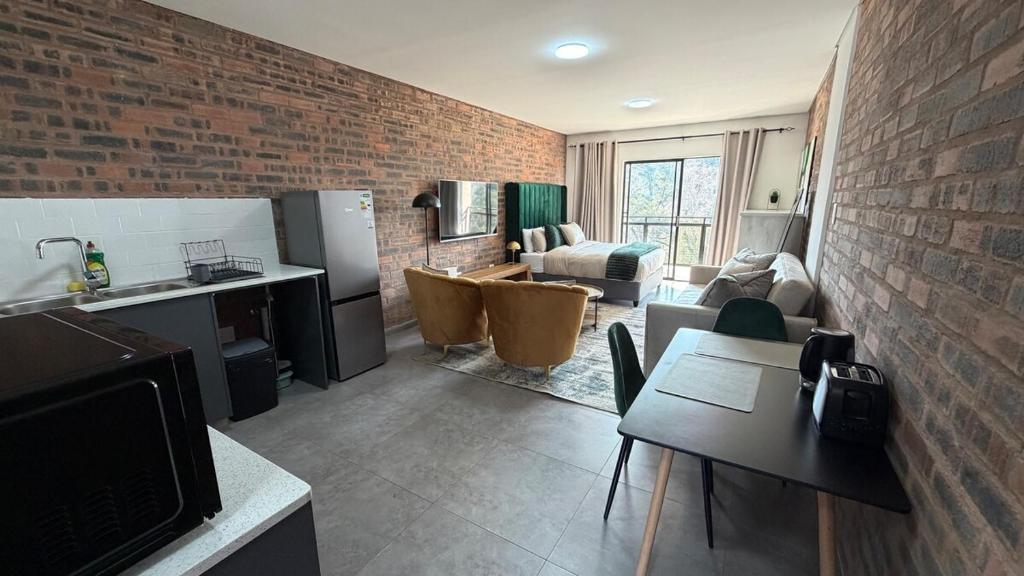 a kitchen and living room with a brick wall at CS Nest Modern Studio Athlone in Pietermaritzburg