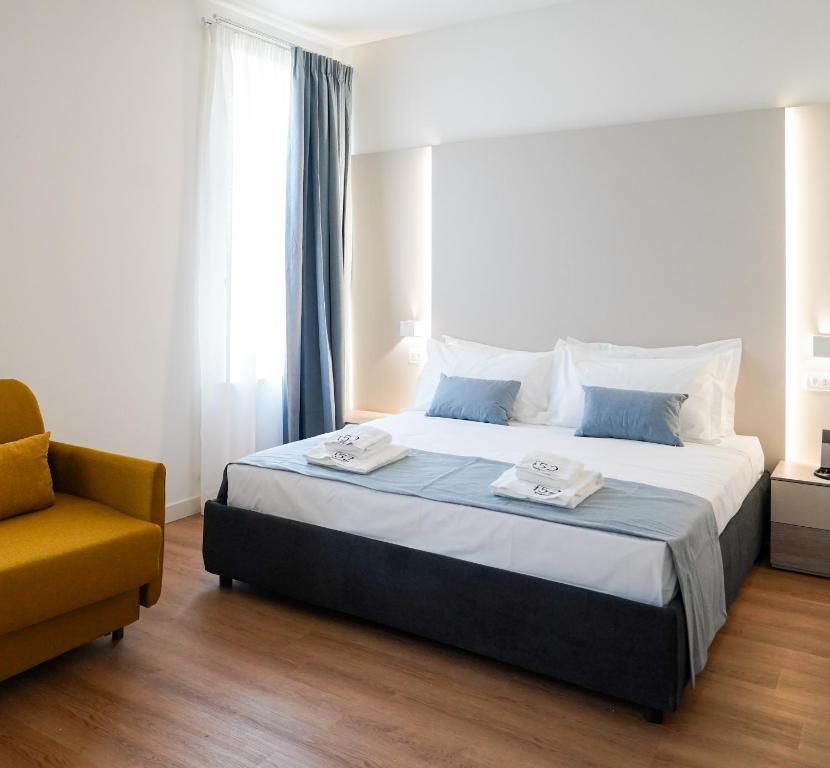 ein Schlafzimmer mit einem großen Bett und einem gelben Stuhl in der Unterkunft Hotel F52 in Parma