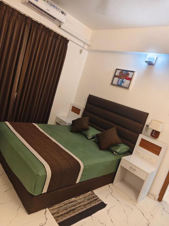 a bedroom with a bed with a green comforter at krishna madhavam in Guruvāyūr