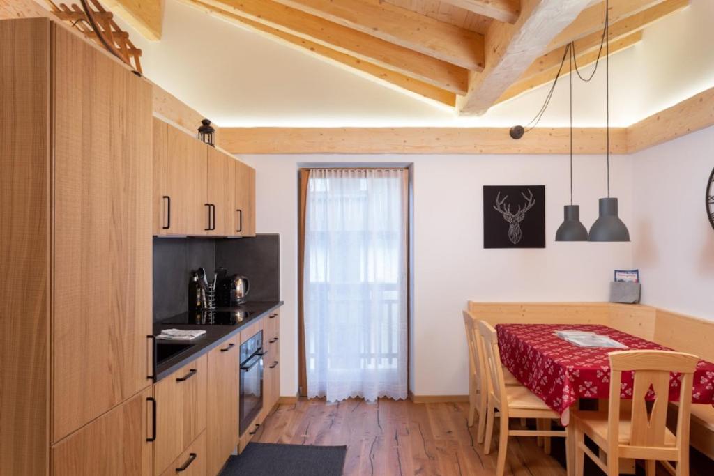 a kitchen and dining room with a table with a red tablecloth at Casa Chris by AMA Val di Fassa in Pozza di Fassa