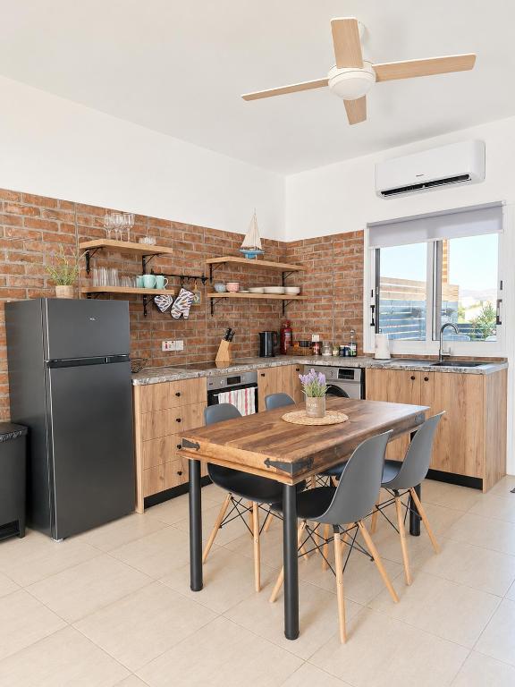 a kitchen with a wooden table and a black refrigerator at Andromeda Apartment in Polis Chrysochous