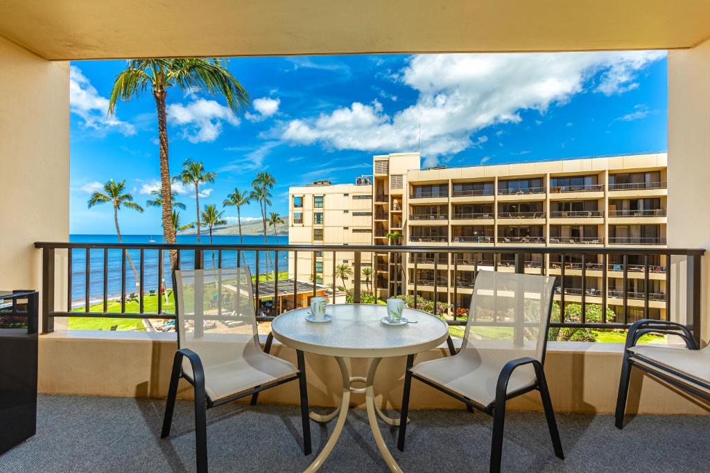 a balcony with a table and chairs and a view of the ocean at SUGAR BEACH RESORT #412 in Kihei