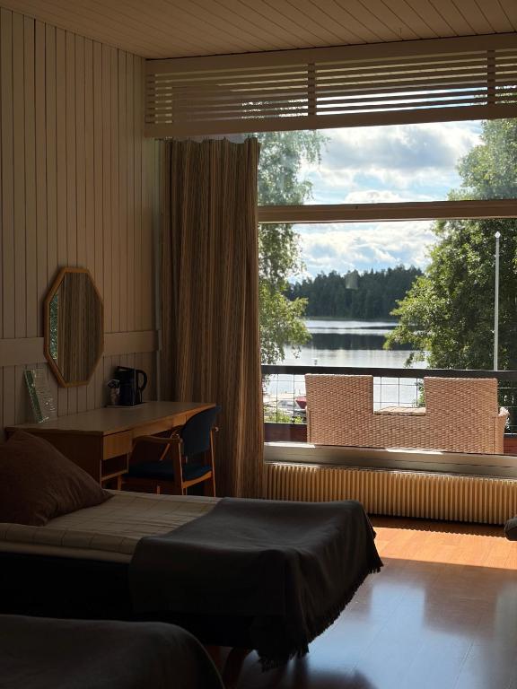 a bedroom with a bed and a desk and a large window at Hotelli Pihkuri in Viitasaari