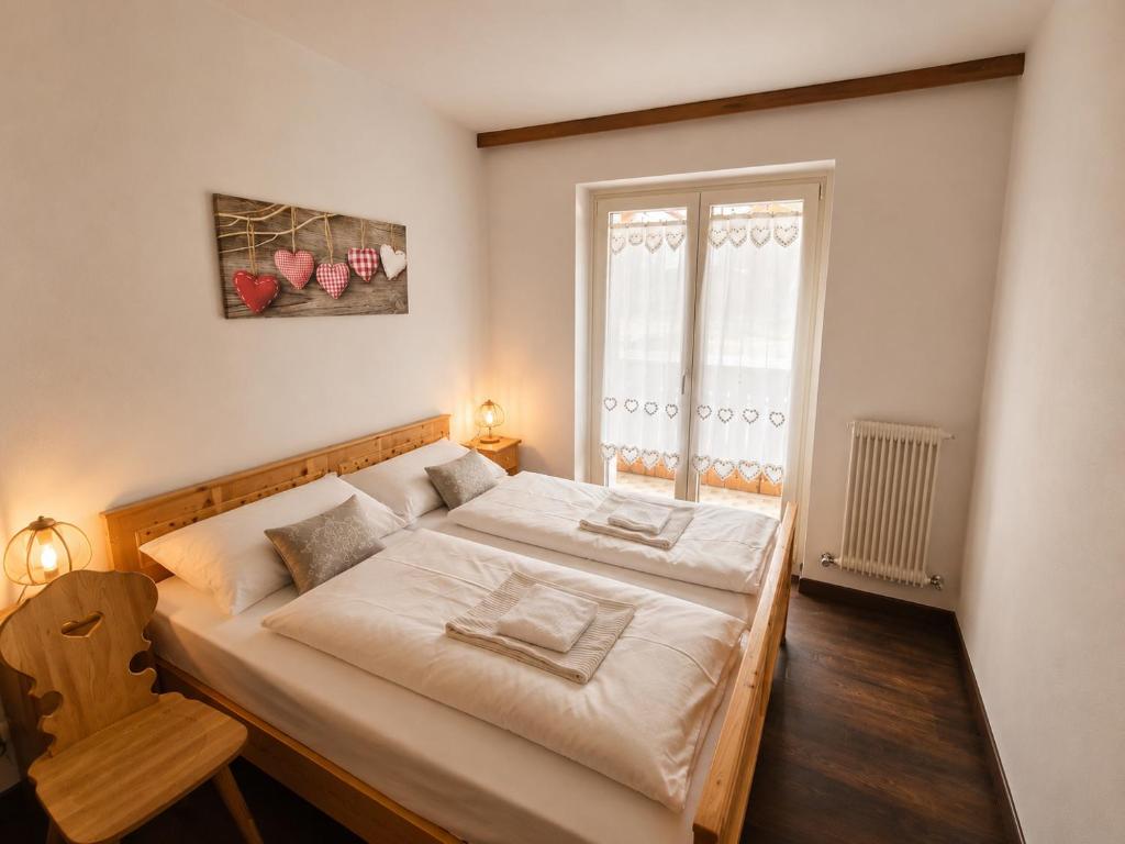 a bedroom with a large bed with white sheets and a window at Appartamento Cuore by AMA Val di Fassa in Campitello di Fassa