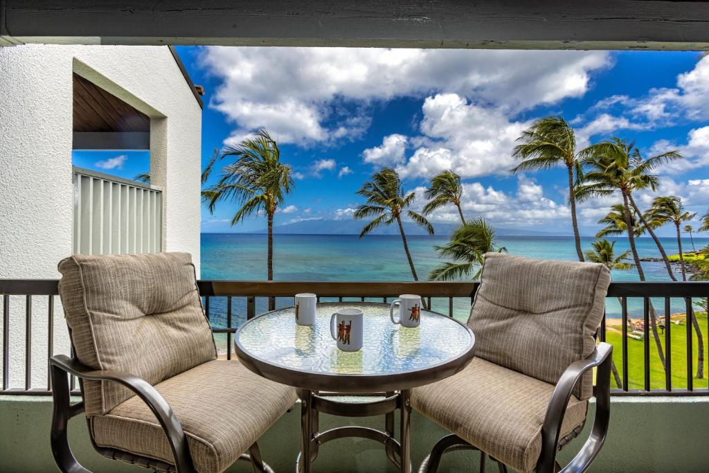 a table and chairs on a balcony with a view of the ocean at Hale Mahina #B-405 in Honokowai