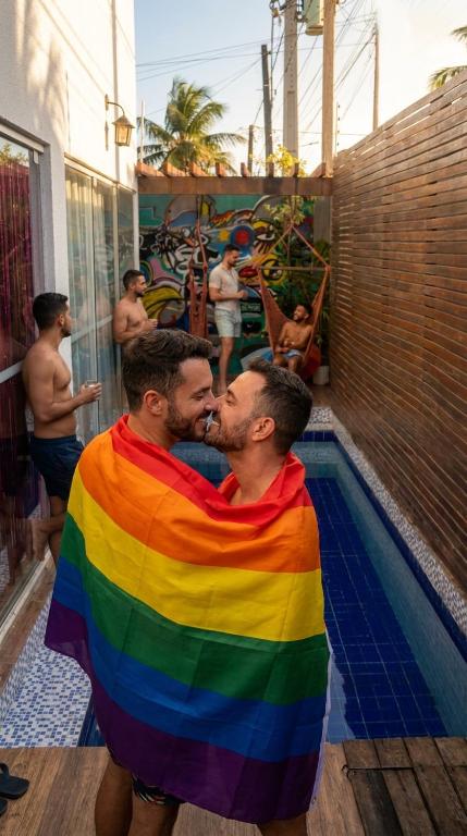 two men wrapped in a rainbow blanket next to a swimming pool at Hostel do Mago in Pipa