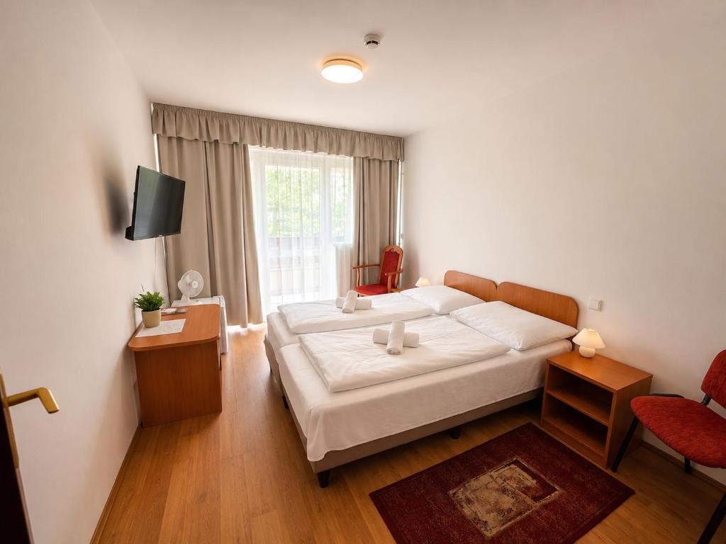 a bedroom with a large bed and a window at PSZ Hotel Beach Földvár in Balatonföldvár