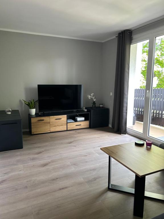 a living room with a flat screen tv and a table at Apartament Opawska in Racibórz