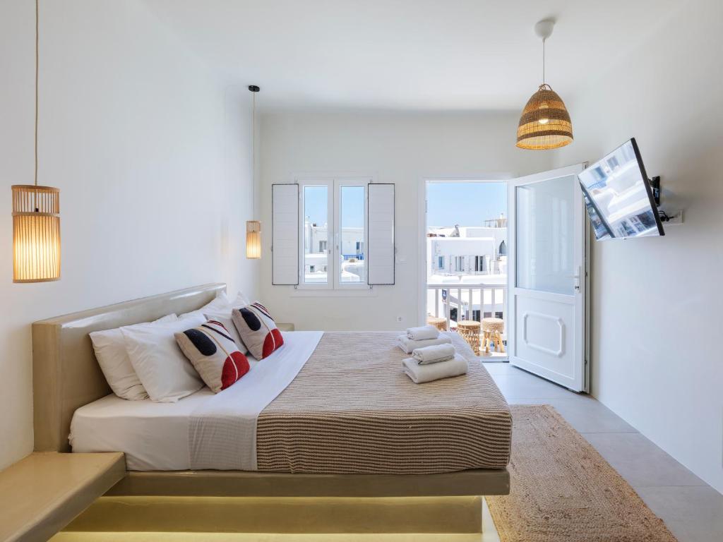 a white bedroom with a bed and a tv at Dival Properties Mykonos 1 & 2 in Megali Ammos