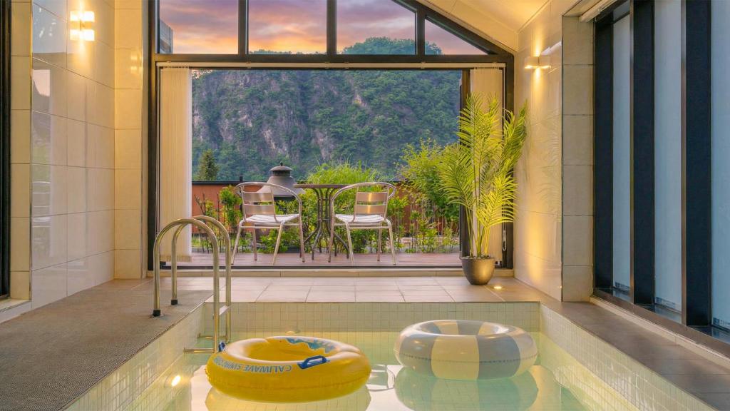 a room with a pool with a table and chairs at Danyang Dandelion Pool Villa in Danyang