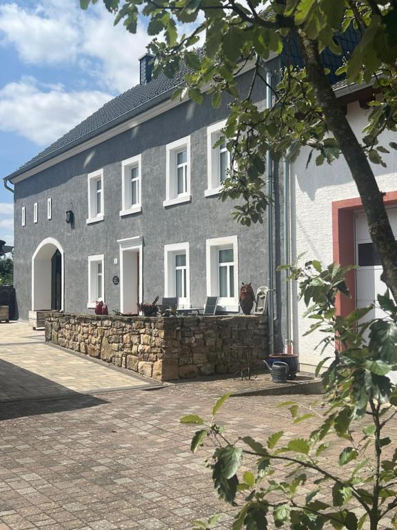 a gray house with a stone wall and a building at Natur pur Eifel in Gerolstein