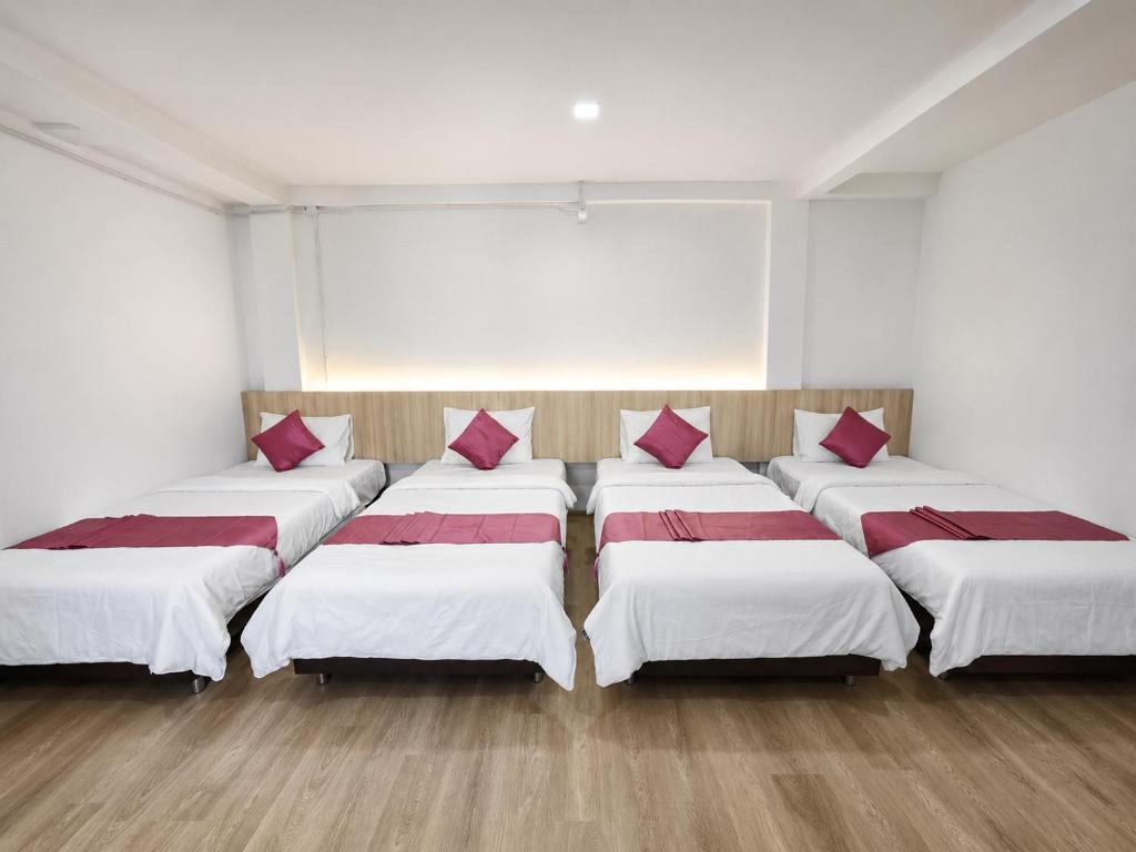 a room with four beds with red pillows on them at The 789 House in Chiang Mai