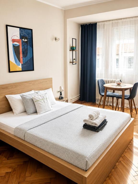 a bedroom with a large bed and a table at Apartman Lena in Belgrade