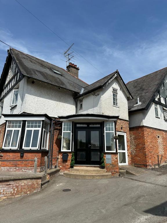 a white and red brick house with a driveway at Cavendish Hotel in High Wycombe