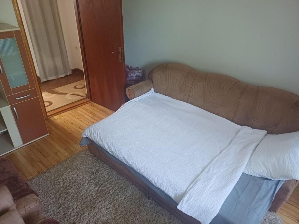 a bedroom with a bed with white sheets and a mirror at Apartman BelSa in Sarajevo