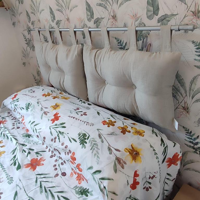 a bed with a floral comforter on top of it at Casa Iris in Somma Lombardo