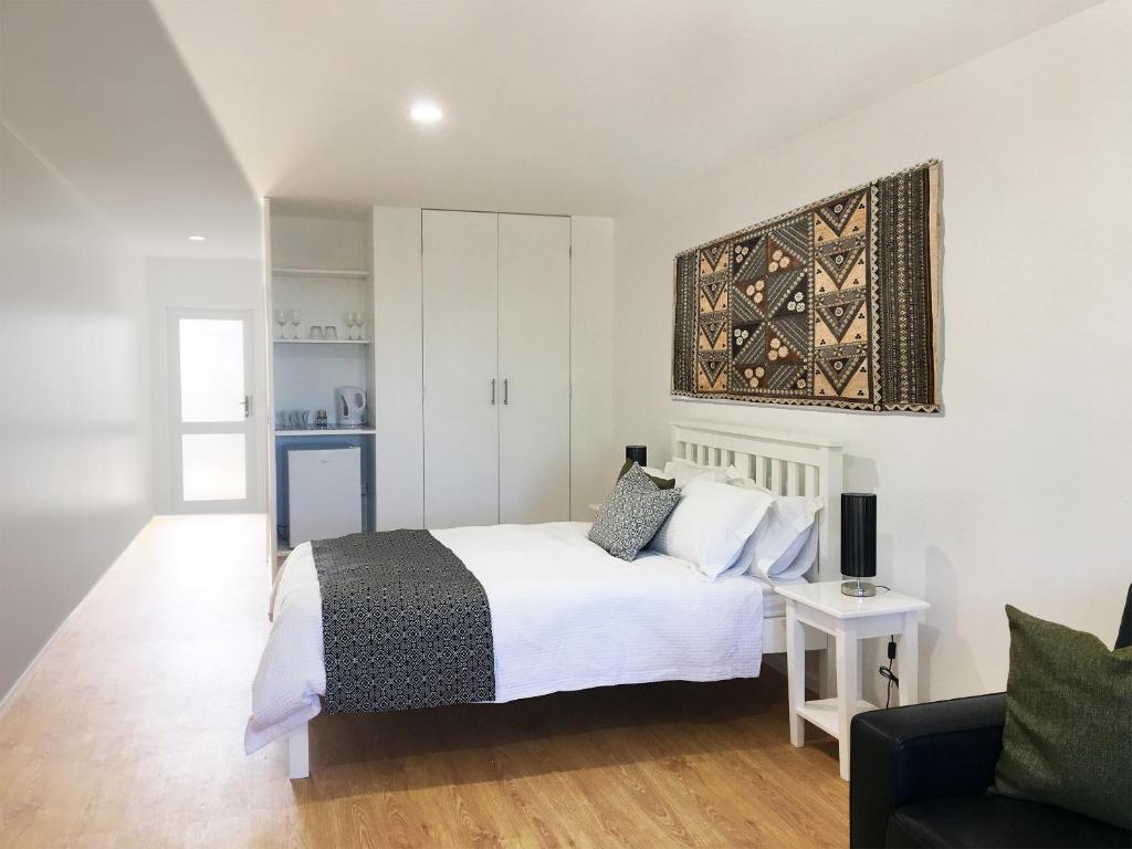 um quarto com uma cama branca e um sofá em House of Tonga em Nuku‘alofa