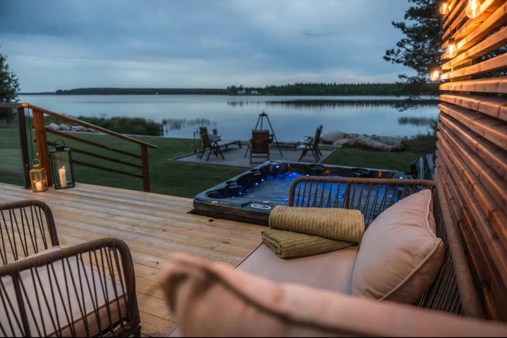 a deck with a hot tub next to a lake at Joulupukin talolla in Rovaniemi