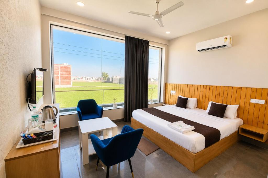 a hotel room with a bed and a large window at Hotel Olive Sunny Enclave, Near Airport Road, Mohali in Kharar