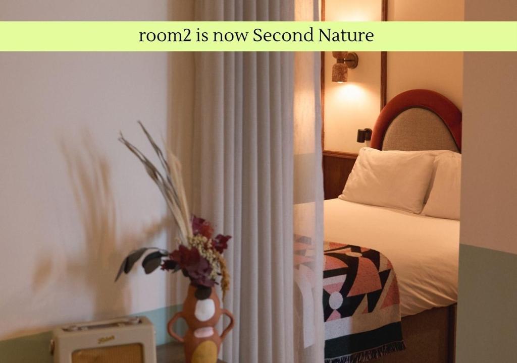 a hotel room with a bed and a vase of flowers at Second Nature Belfast in Belfast