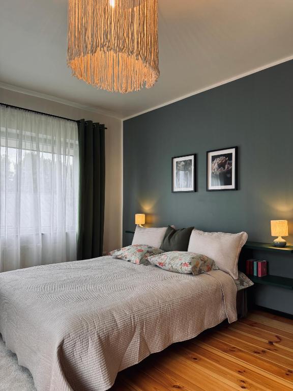 a bedroom with a large bed and a chandelier at The Forest room in Ikšķile