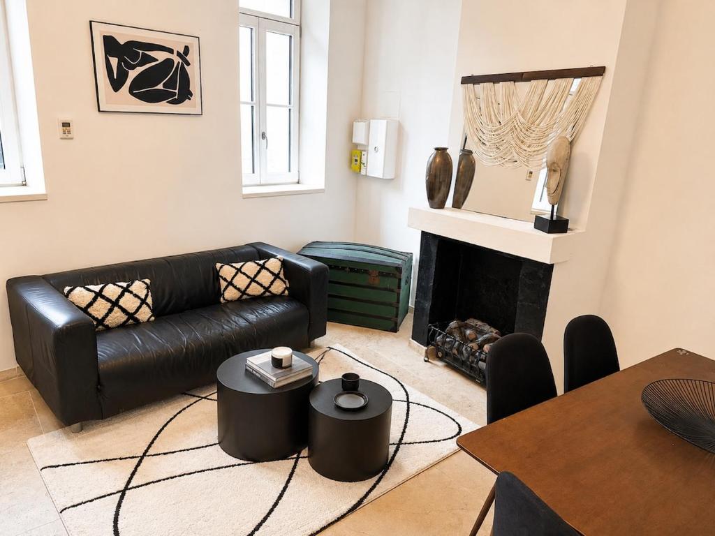a living room with a black leather couch and a fireplace at Maison de ville hypercentre Béthune in Béthune