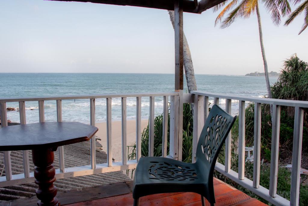 a table and chairs on a balcony overlooking the beach at Little Pumpkin Cabanas & seafood restaurant in Tangalle