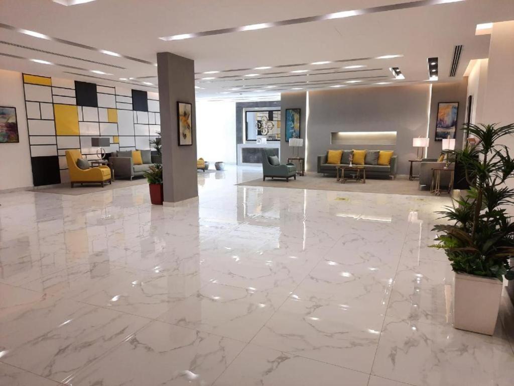a lobby with a large marble floor and yellow chairs at شقق الآجنحة التنفيذية للشقق المخدومة in Riyadh