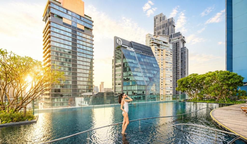 a woman in a infinity pool in a city with tall buildings at Grande Centre Point Sukhumvit 55 Thong Lo in Bangkok
