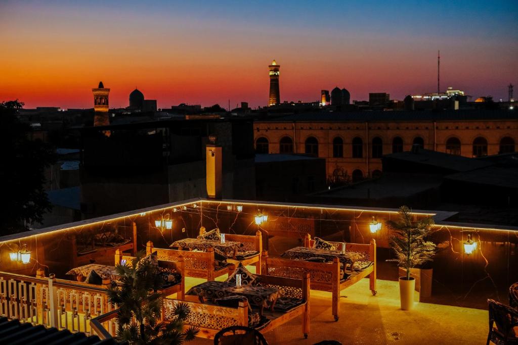 a rooftop restaurant with a view of the city at night at Aida hotel PREMIUM in Bukhara