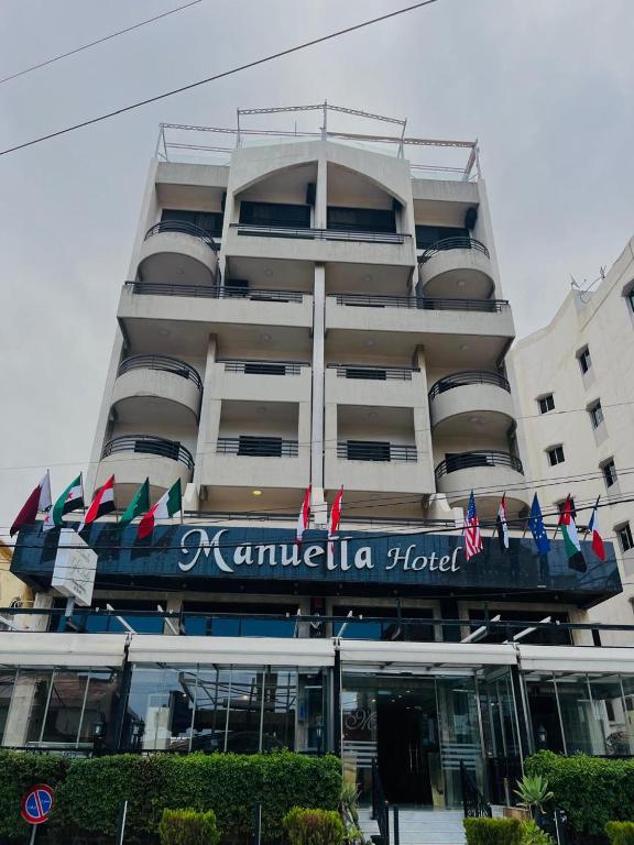 a building with a hotel with flags in front of it at Manuella Hotel in Ed Dkârîne